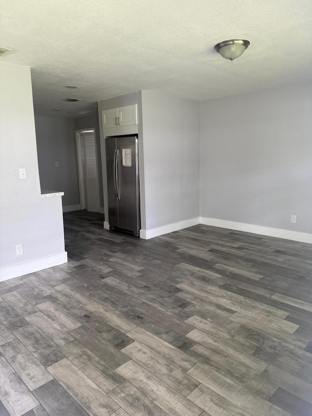 empty room with baseboards, dark wood-style flooring, and a textured ceiling