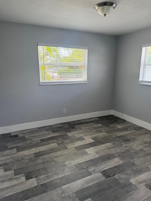 spare room featuring dark wood finished floors and baseboards