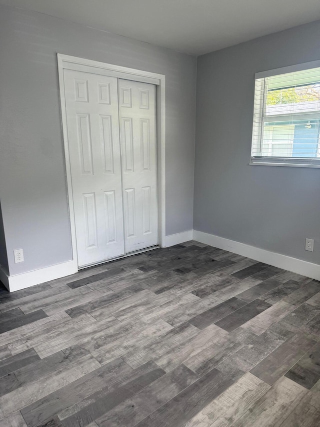 unfurnished bedroom featuring a closet, wood finished floors, and baseboards