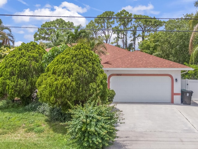view of front of home featuring driveway, stucco siding, roof with shingles, and a garage