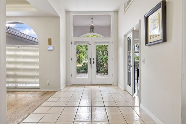 foyer entrance featuring light tile patterned flooring, baseboards, and french doors