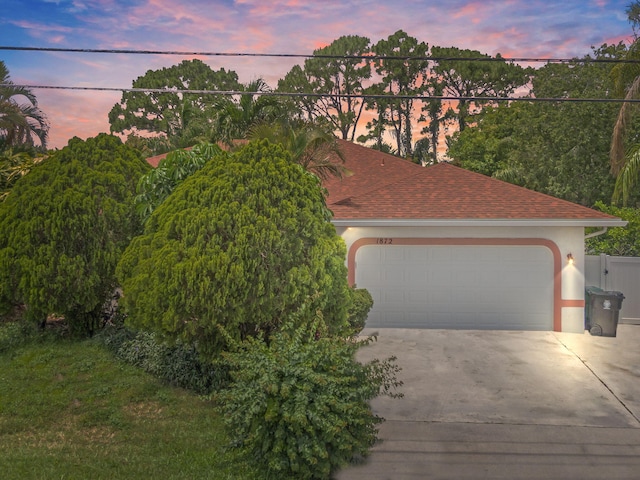 view of front of property featuring a shingled roof, stucco siding, driveway, and an attached garage