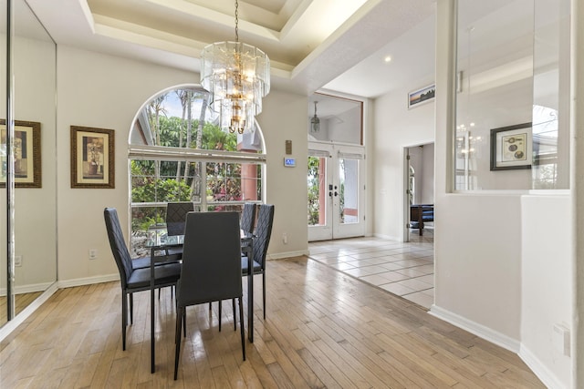 dining room with a tray ceiling, an inviting chandelier, hardwood / wood-style flooring, and baseboards