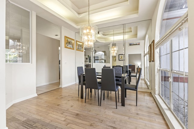 dining room with baseboards, a raised ceiling, an inviting chandelier, and light wood-style flooring