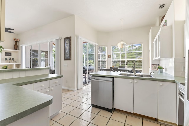 kitchen featuring a peninsula, a sink, white cabinets, stainless steel dishwasher, and visible vents