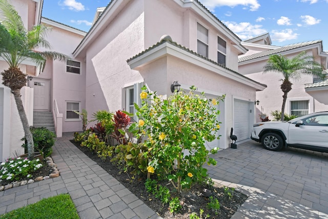 3003 Fairway Dr N, Jupiter, FL 33477 - view of home's exterior with stucco siding, an attached garage, and driveway