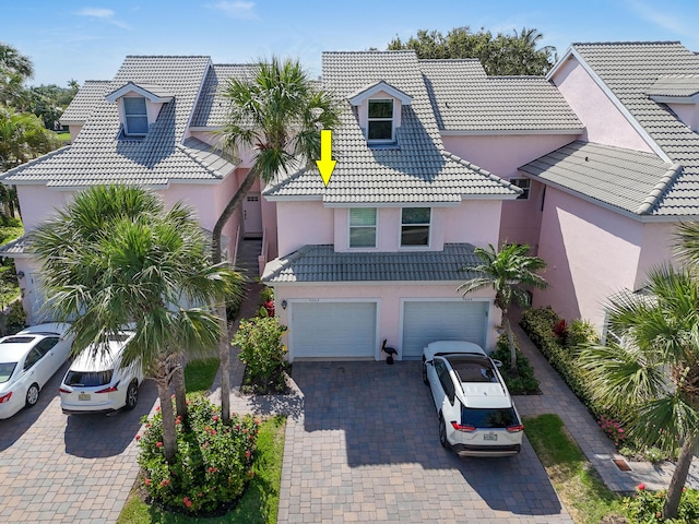 3003 Fairway Dr N, Jupiter, FL 33477 - view of front facade featuring stucco siding, a tiled roof, decorative driveway, and an attached garage