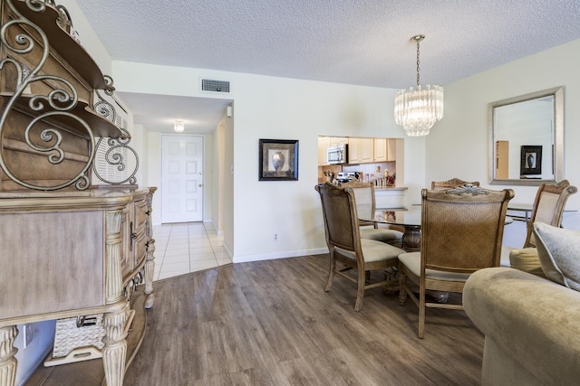 13403 Touchstone Pl Unit A-202, Palm Beach Gardens, FL 33418 - dining area featuring a chandelier, wood finished floors, a textured ceiling, and baseboards