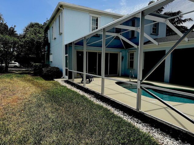 2616 E Community Dr, Jupiter, FL 33458 - back of property with a patio, glass enclosure, a yard, an outdoor pool, and stucco siding