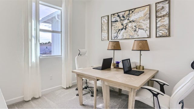 home office with baseboards and light colored carpet