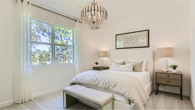 bedroom featuring light colored carpet, a chandelier, and baseboards