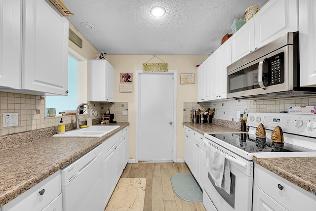 1742 SW Hampshire Ln, Port Saint Lucie, FL 34953 - kitchen featuring white appliances, a sink, light wood-style floors, white cabinets, and a textured ceiling