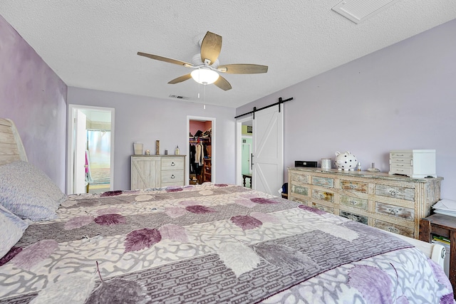 1742 SW Hampshire Ln, Port Saint Lucie, FL 34953 - bedroom with a barn door, a spacious closet, a closet, a textured ceiling, and ceiling fan