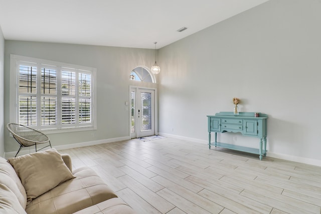 living area featuring baseboards, light wood-style floors, and visible vents
