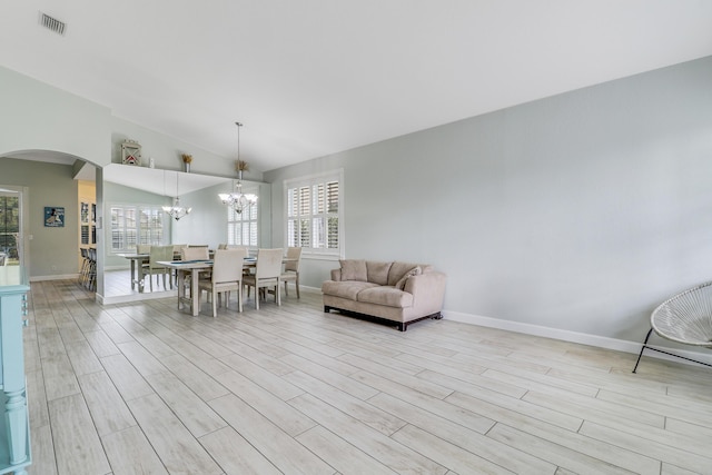living room featuring a chandelier, baseboards, light wood-style flooring, and arched walkways
