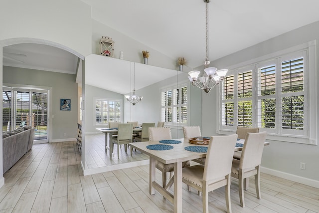 dining room with lofted ceiling, light wood-type flooring, baseboards, arched walkways, and a notable chandelier