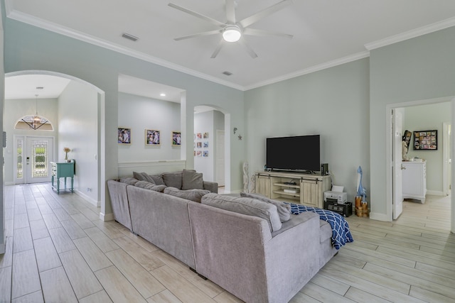 living room with visible vents, ceiling fan, arched walkways, light wood-style floors, and ornamental molding