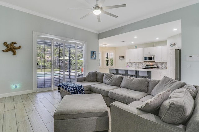 living area featuring ceiling fan, crown molding, baseboards, and recessed lighting