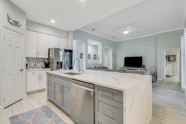 kitchen with a sink, stainless steel appliances, open floor plan, gray cabinets, and arched walkways