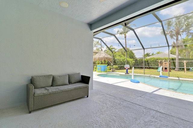 outdoor pool featuring glass enclosure, a patio, and outdoor lounge area