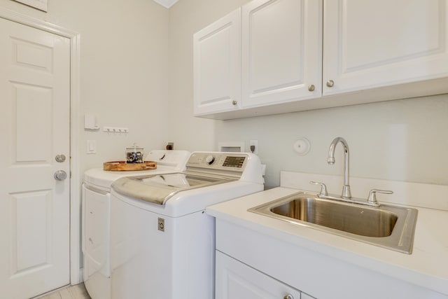 washroom featuring washer and dryer, cabinet space, and a sink