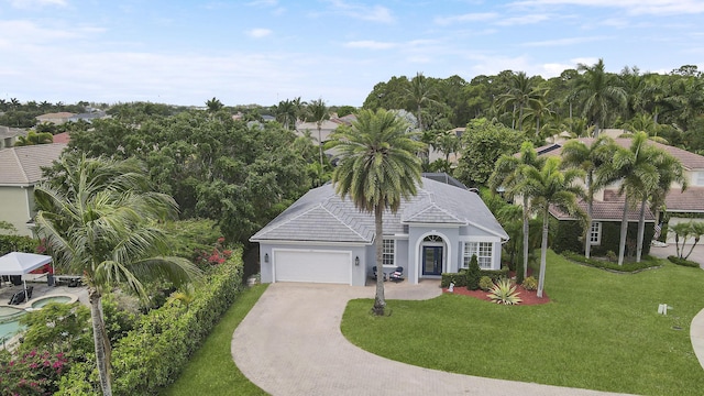 view of front of home featuring driveway, an attached garage, stucco siding, a tile roof, and a front lawn