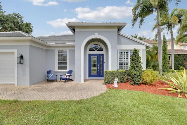 entrance to property with a lawn, stucco siding, a tiled roof, and an attached garage