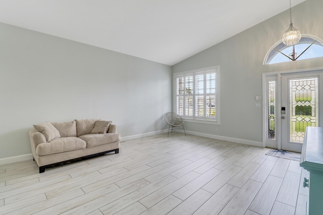 interior space with light wood finished floors, vaulted ceiling, baseboards, and a notable chandelier