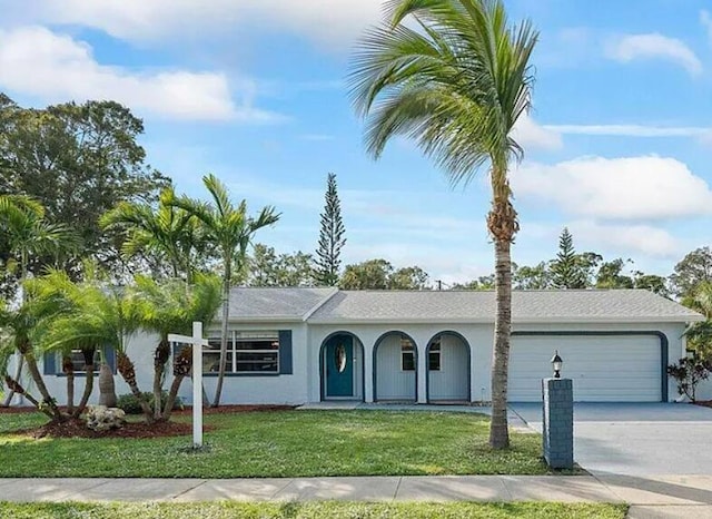 ranch-style house with driveway, a garage, a front yard, and stucco siding