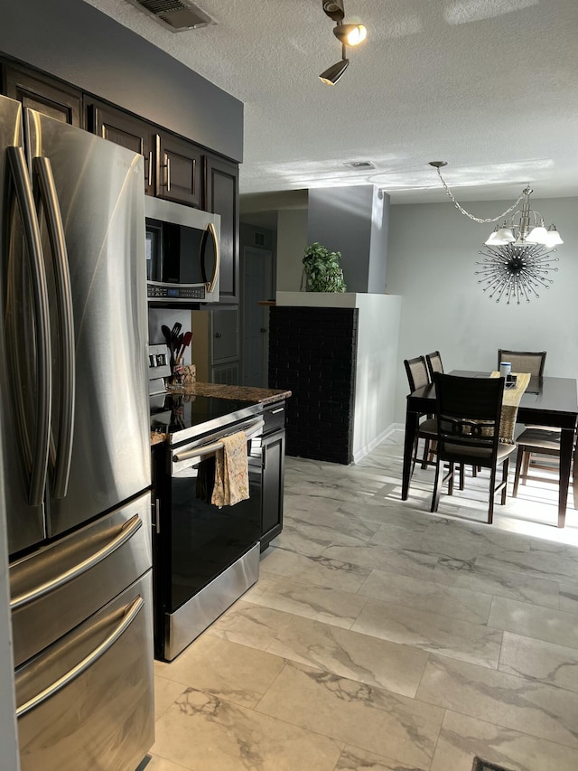 kitchen with appliances with stainless steel finishes, light marble finish floors, a chandelier, and a textured ceiling