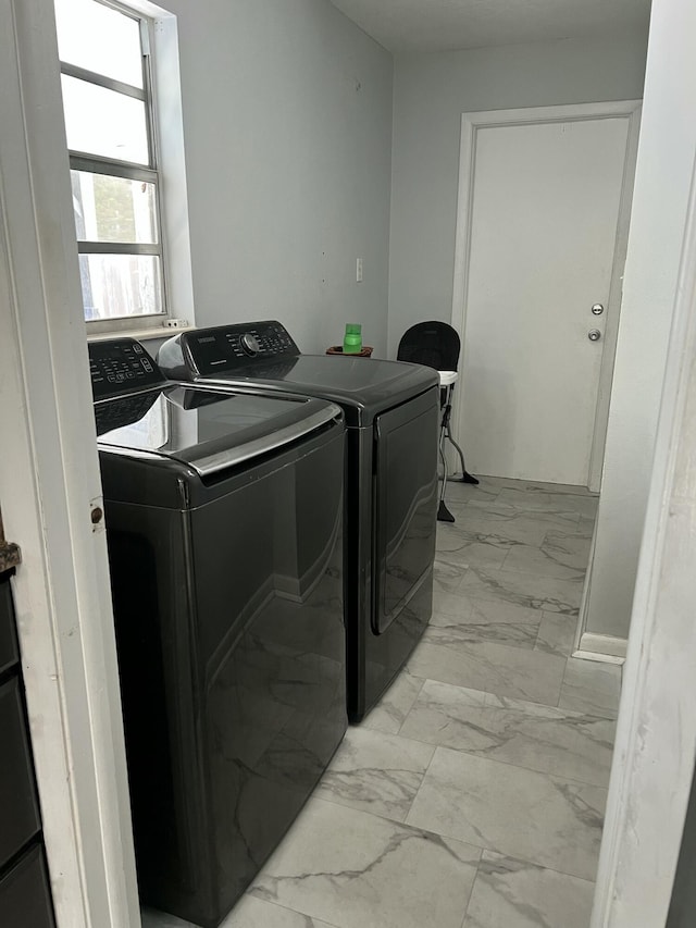 washroom with washing machine and dryer and light marble finish flooring