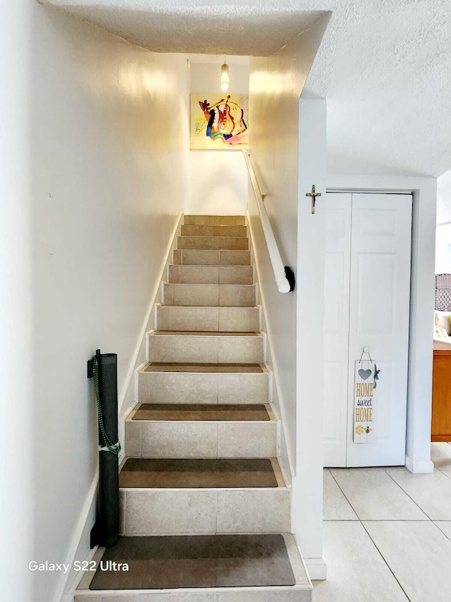 staircase featuring tile patterned floors and a textured ceiling