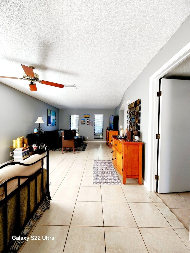 interior space featuring light tile patterned floors, ceiling fan, and a textured ceiling