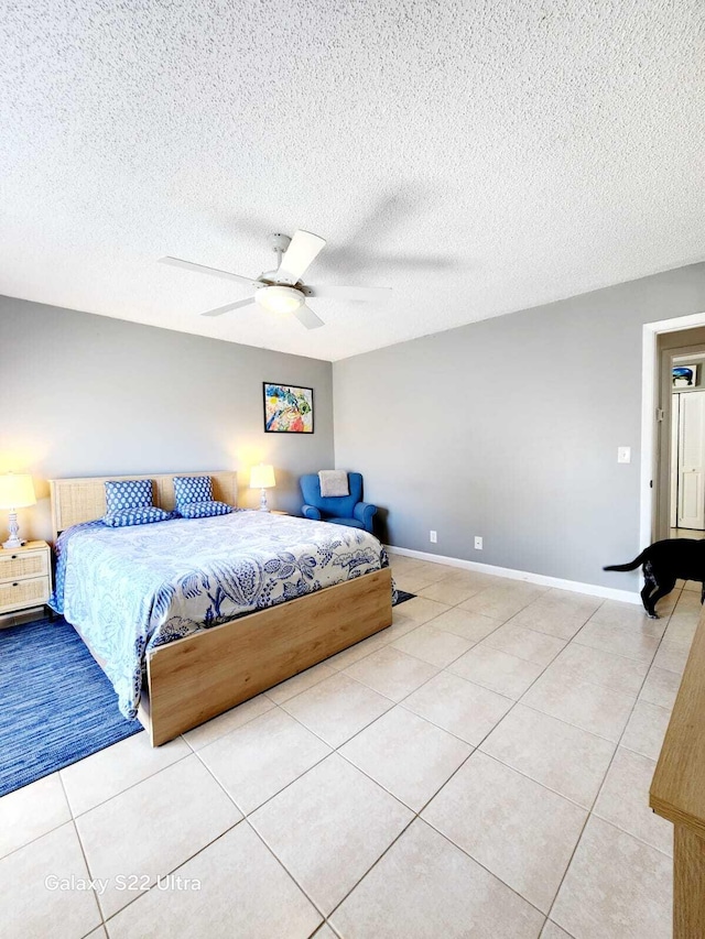 bedroom featuring a ceiling fan, tile patterned flooring, a textured ceiling, and baseboards