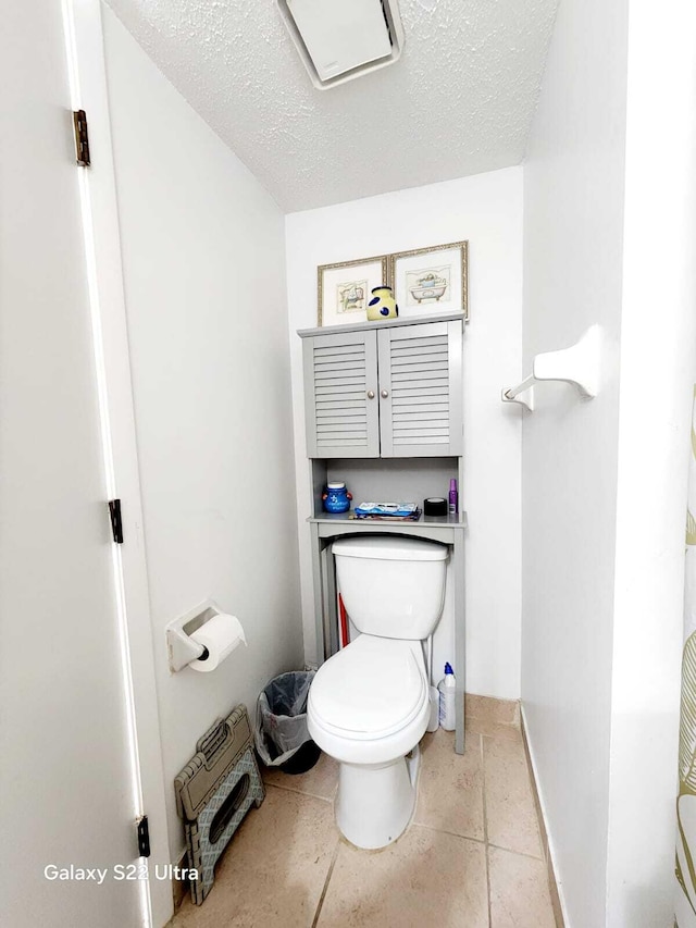 bathroom featuring toilet, a textured ceiling, and baseboards