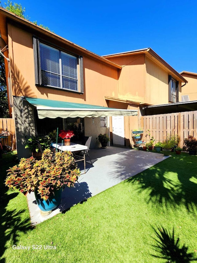 rear view of house with a lawn, a patio area, and fence