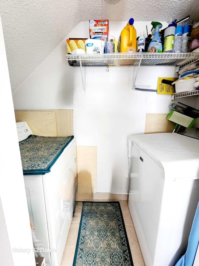 interior space with washing machine and dryer, laundry area, a textured ceiling, and baseboards