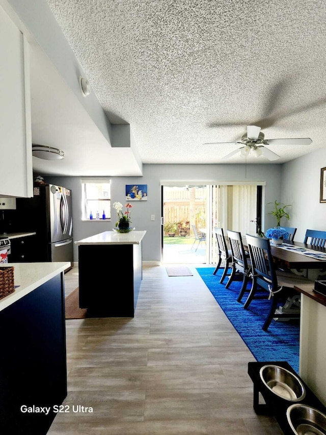 dining room featuring ceiling fan, a textured ceiling, and wood finished floors