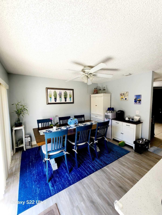 dining area featuring a ceiling fan, a textured ceiling, and wood finished floors