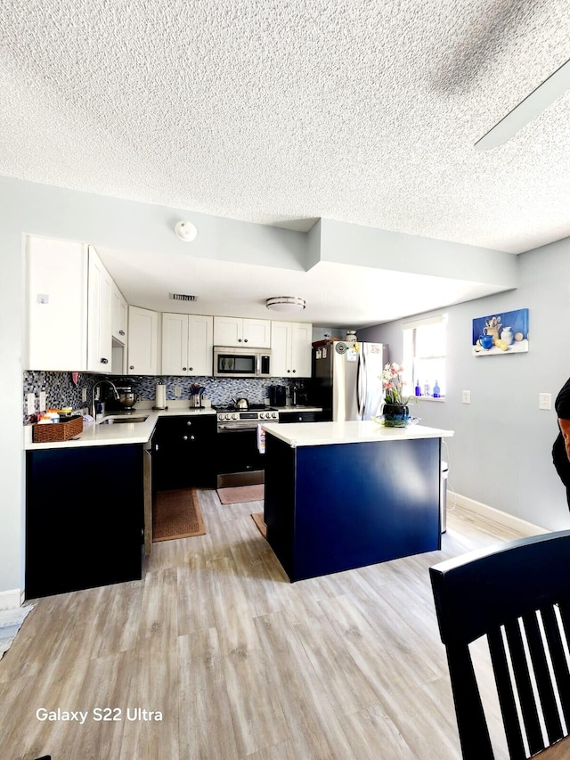 kitchen with light countertops, stainless steel appliances, a center island, and a textured ceiling