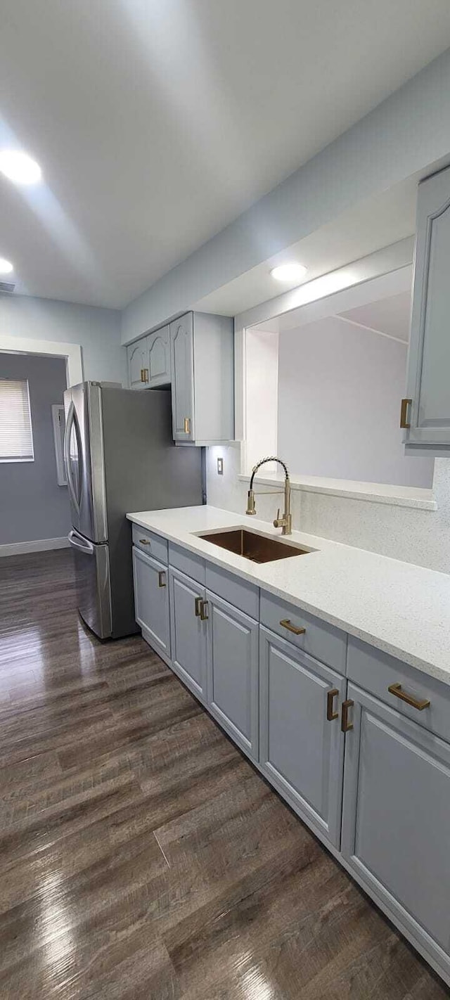 kitchen featuring a sink, freestanding refrigerator, dark wood finished floors, gray cabinets, and light countertops
