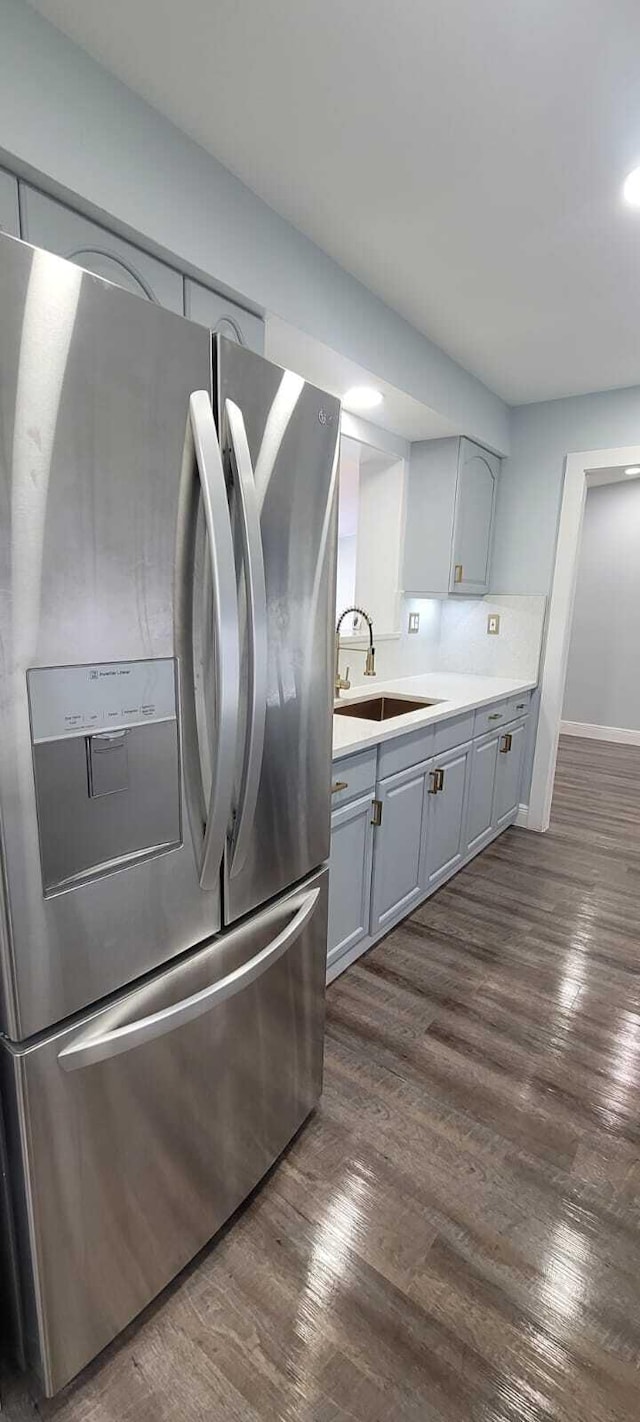 kitchen with a sink, stainless steel fridge with ice dispenser, dark wood-type flooring, light countertops, and gray cabinets