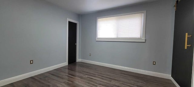 empty room featuring baseboards and dark wood-style floors