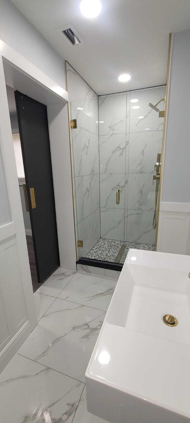 full bath featuring a marble finish shower, a sink, a wainscoted wall, visible vents, and marble finish floor