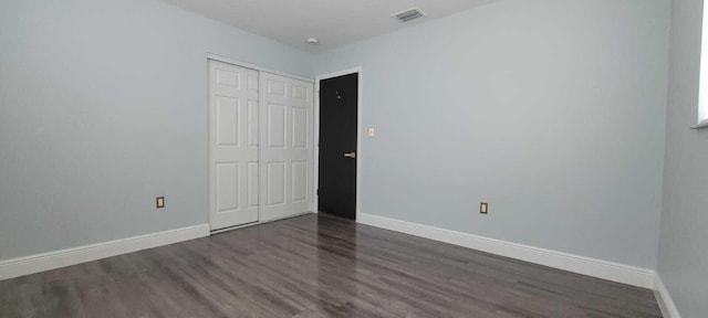 unfurnished room featuring baseboards, visible vents, and wood finished floors