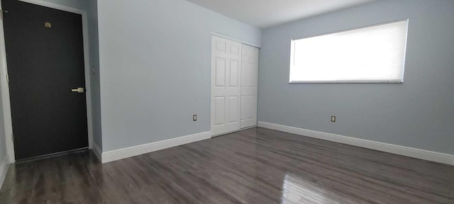 unfurnished bedroom featuring baseboards, a closet, and wood finished floors
