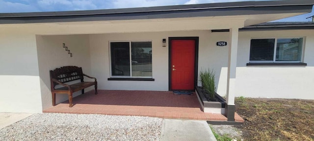 doorway to property featuring stucco siding and a porch
