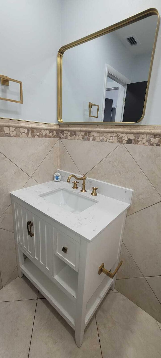 bathroom with tile walls, a wainscoted wall, vanity, visible vents, and tile patterned floors