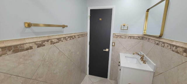 bathroom with wainscoting, vanity, and tile walls