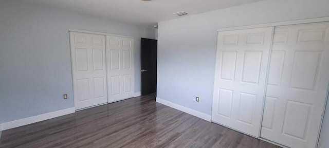 unfurnished bedroom with visible vents, dark wood-style flooring, and baseboards